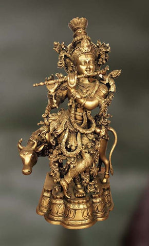 Brass sculpture of Lord Krishna playing flute with a cow in the tow 