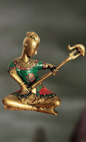 Brass-Stone sculpture of man playing long musical pipe  